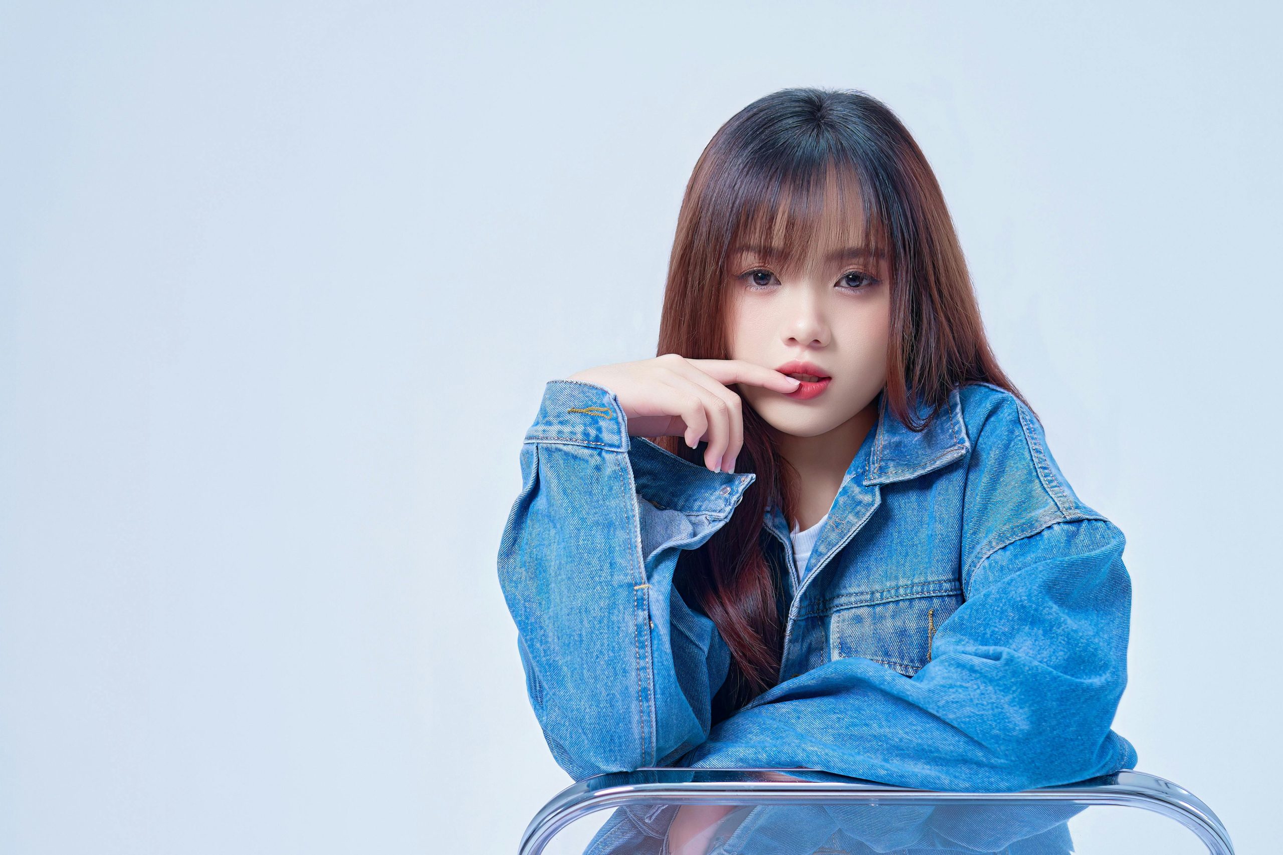 woman in a denim jacket with long hair and wispy bangs