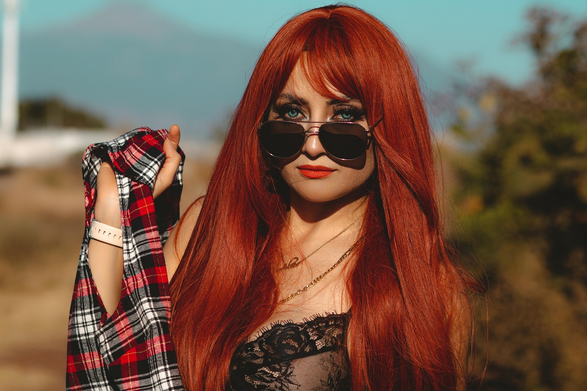 edgy woman with long, red hair and side swept bangs